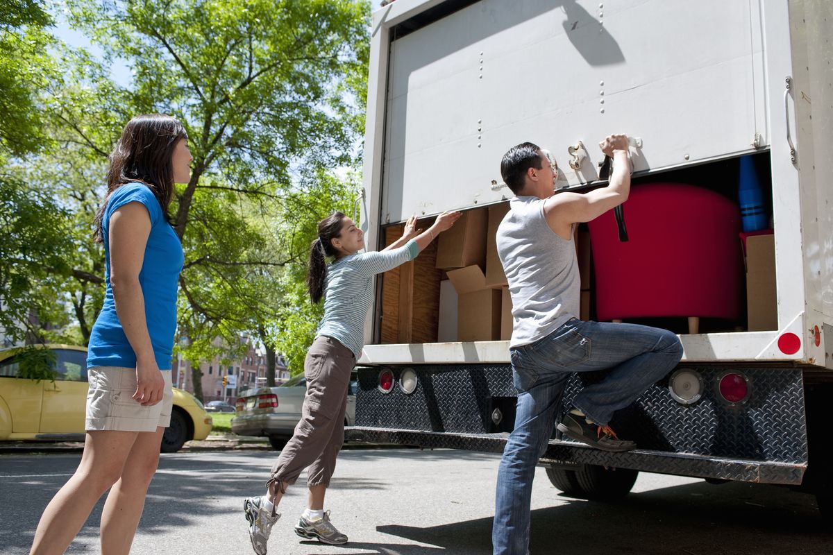 Moving crew loading cardboard boxes into the back of a moving truck